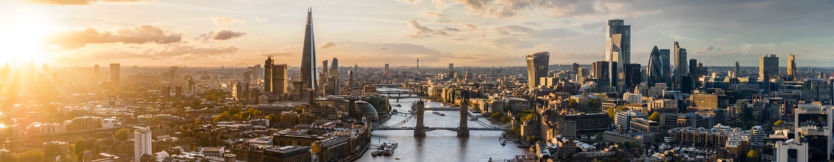 Wide panoramic view to the modern skyline of London, United Kingdom, along the Thames river during sunset time